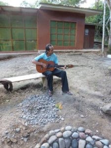 Singing beauty- Ferd practicing the guitar by the firepit, Okopua at the back